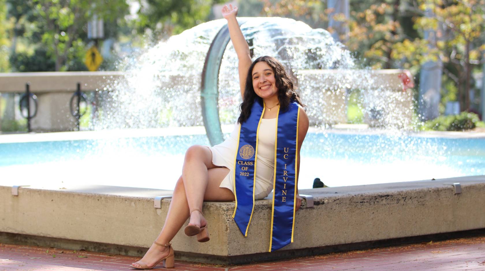 Lili Castillo in her UC Irvine graduation stole in front of a fountain