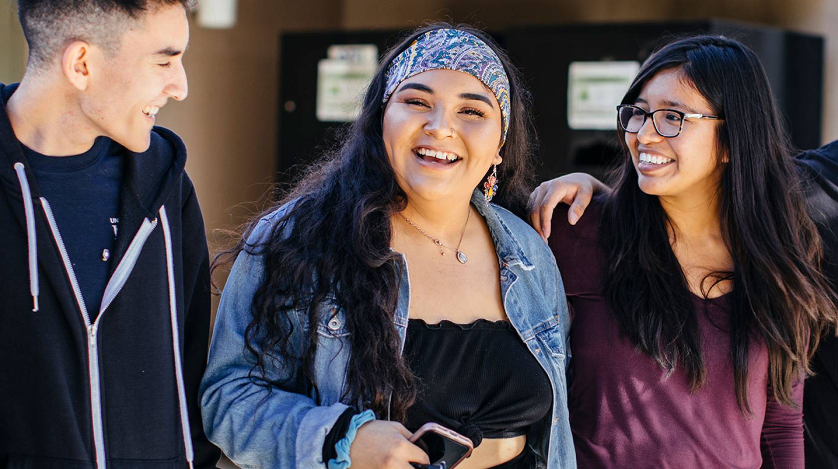 Three students of color smiling and chatting together at UC Merced