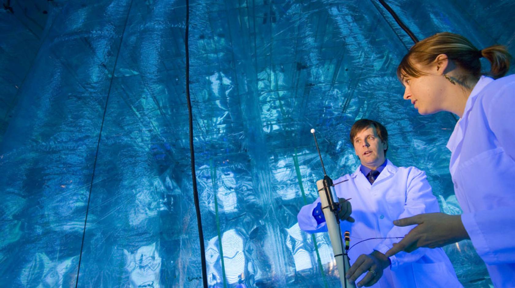 Two researchers in a lab with a bright blue glowing wall