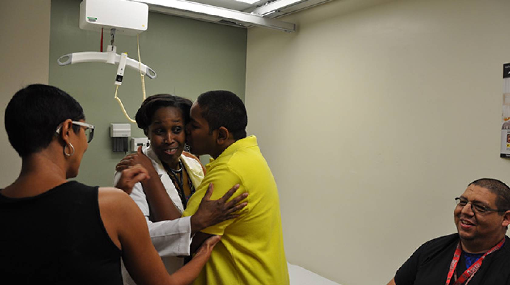 Zulmira T. (left) watches as her son Kobe B. (yellow shirt) expresses his delight in seeing Dr. Emma Simmons. Alfonso Guzman, a licensed vocation nurse assigned to Kobe B., is seen on the right.