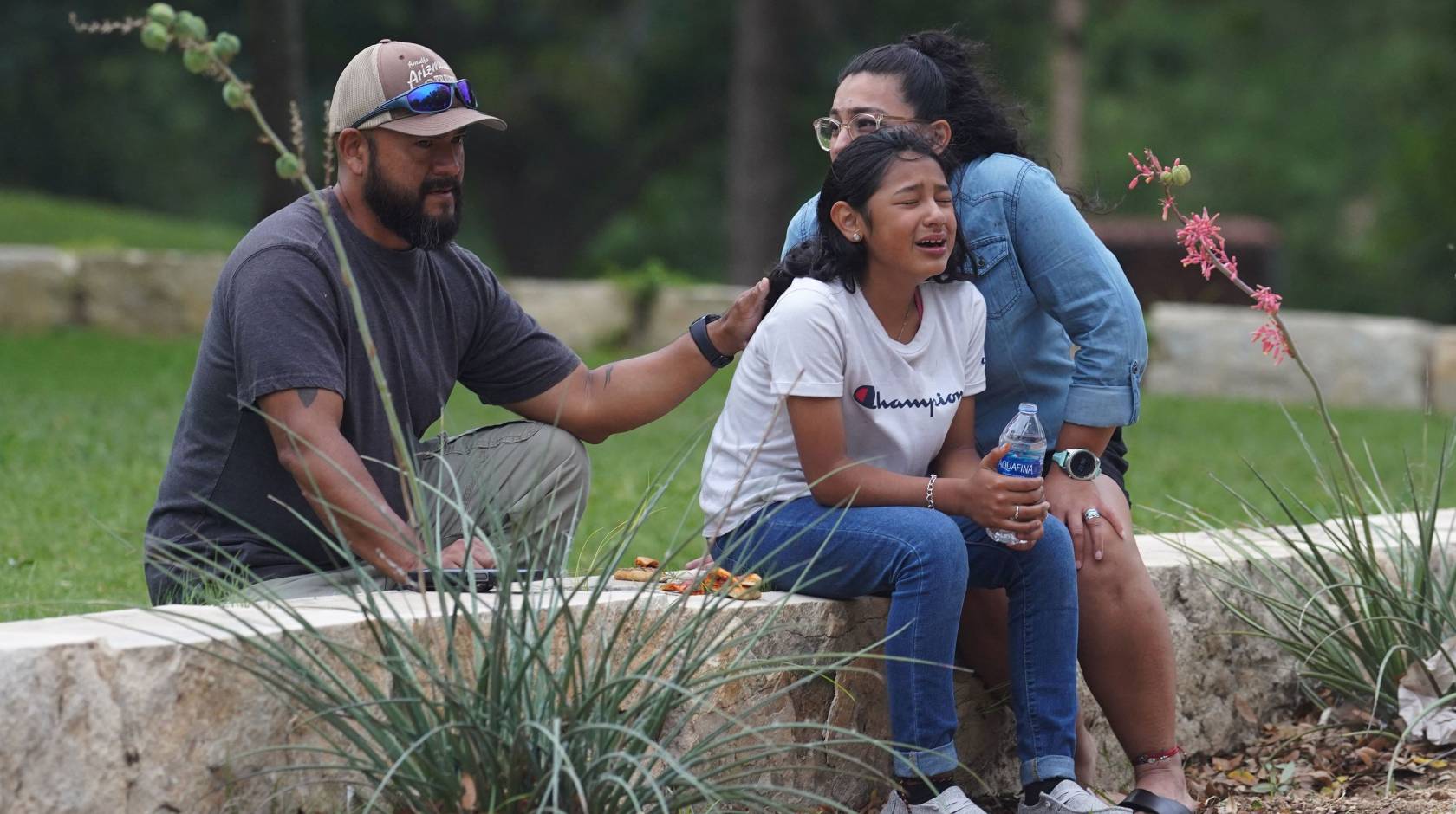 A girl cries outside the Willie de Leon Civic Center in Uvalde, Texas, on May 24, 2022, surrounded by two adults