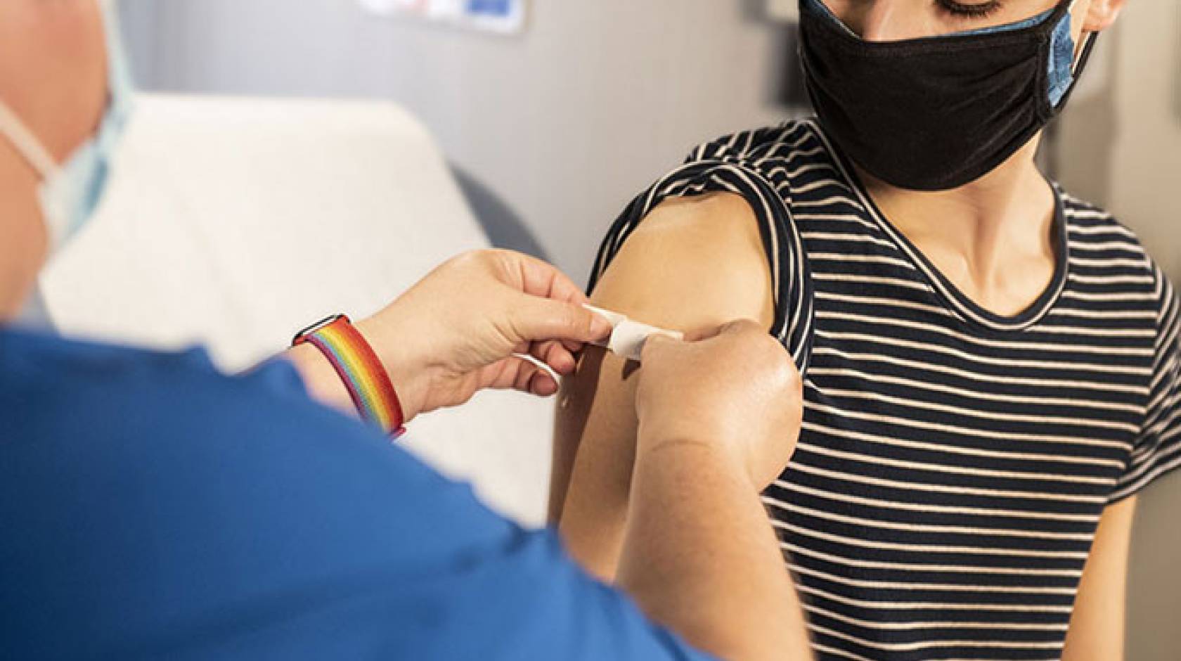 A masked person getting a bandage after getting a shot