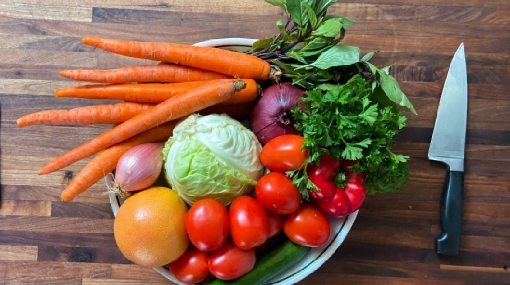 A plate of raw vegetables next to a knife