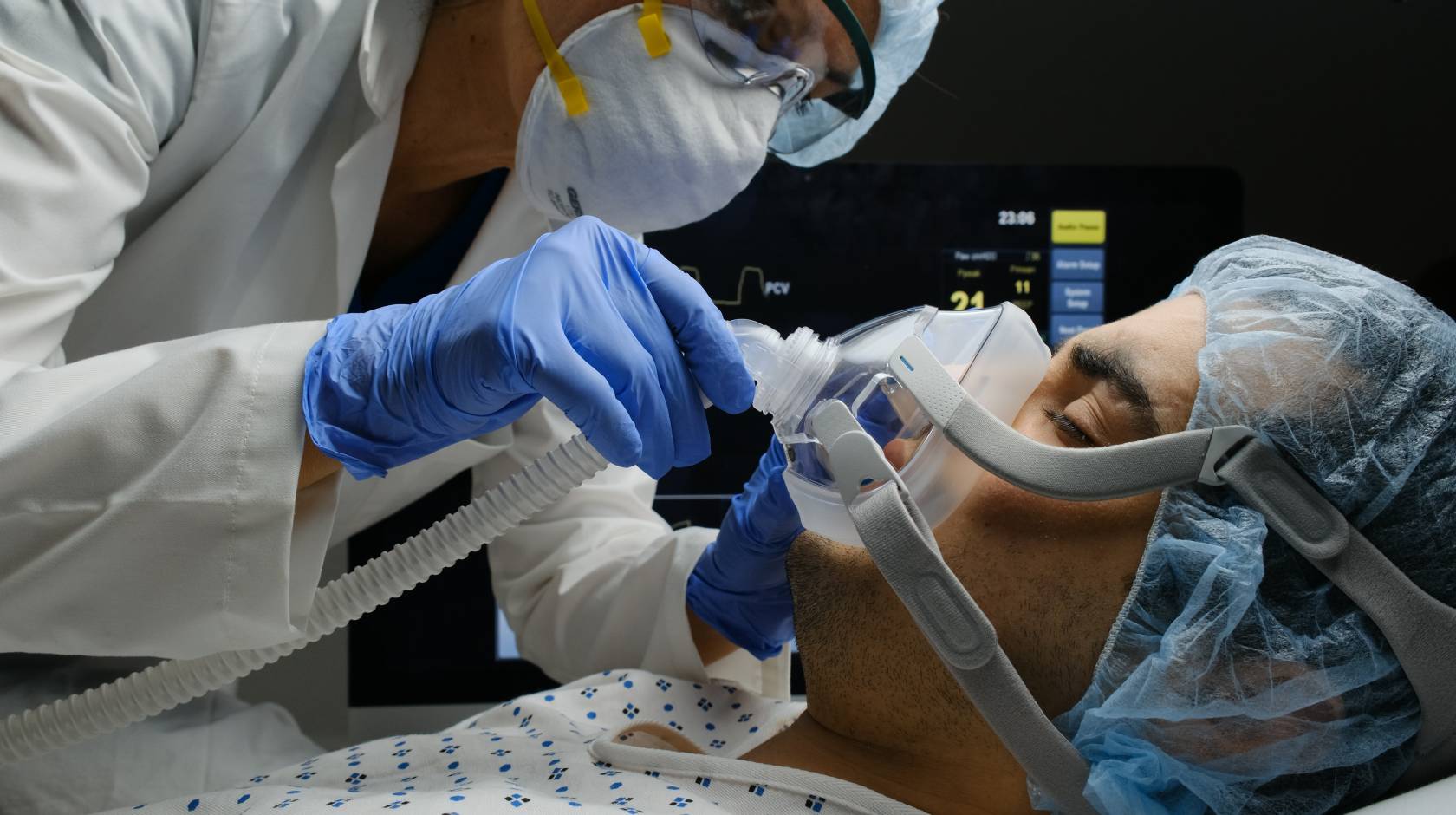 A COVID-19 patient on a ventilator being checked by a doctor