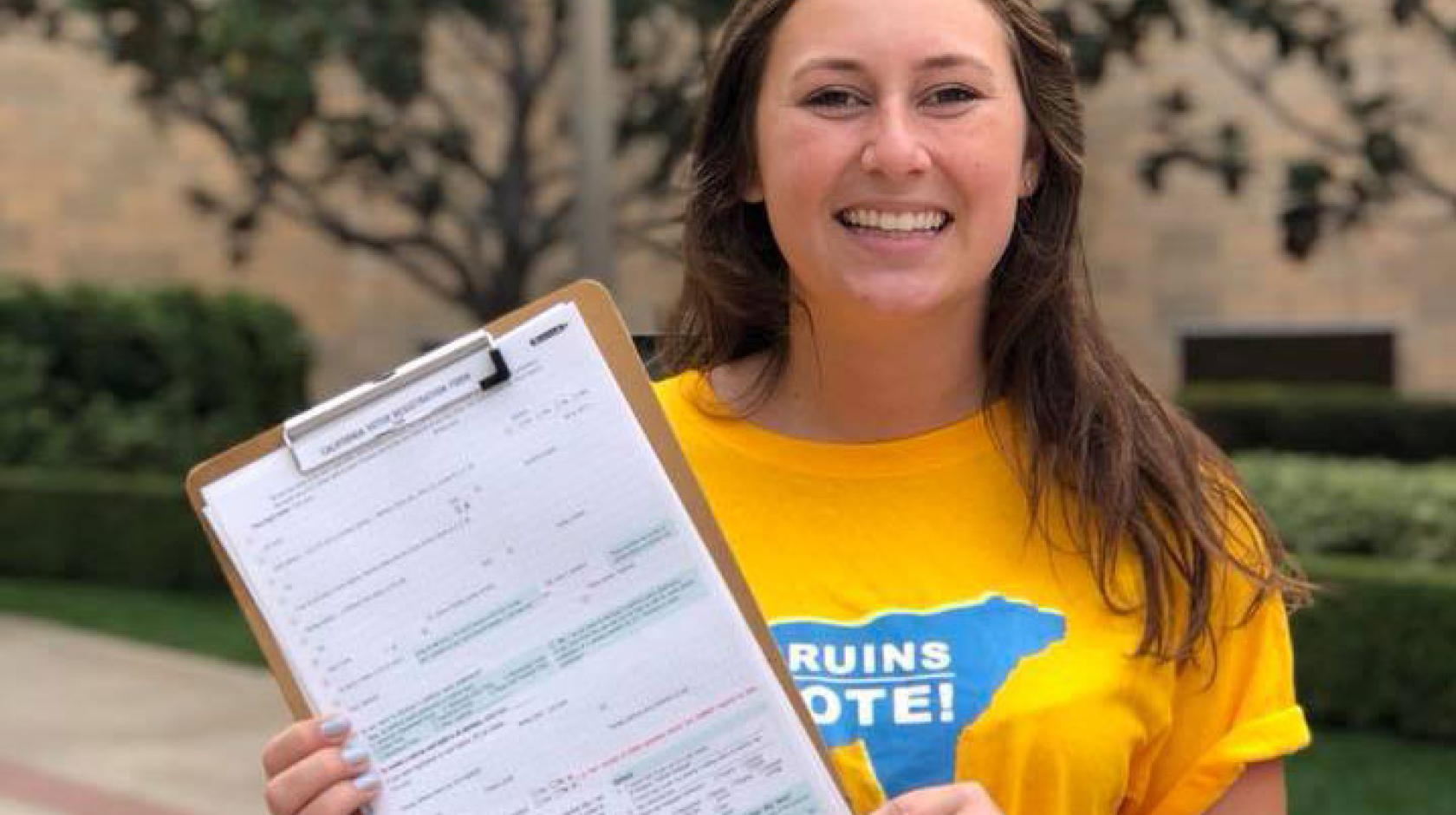 Young woman with Bruins Vote T-shirt holds up voter registration form