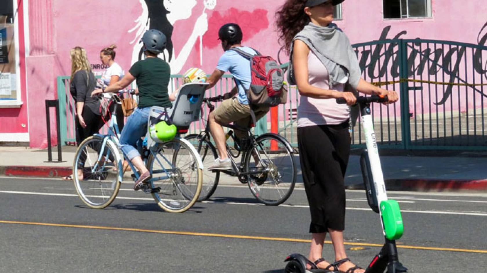 A woman rides a Lime scooter on the street in Santa Monica