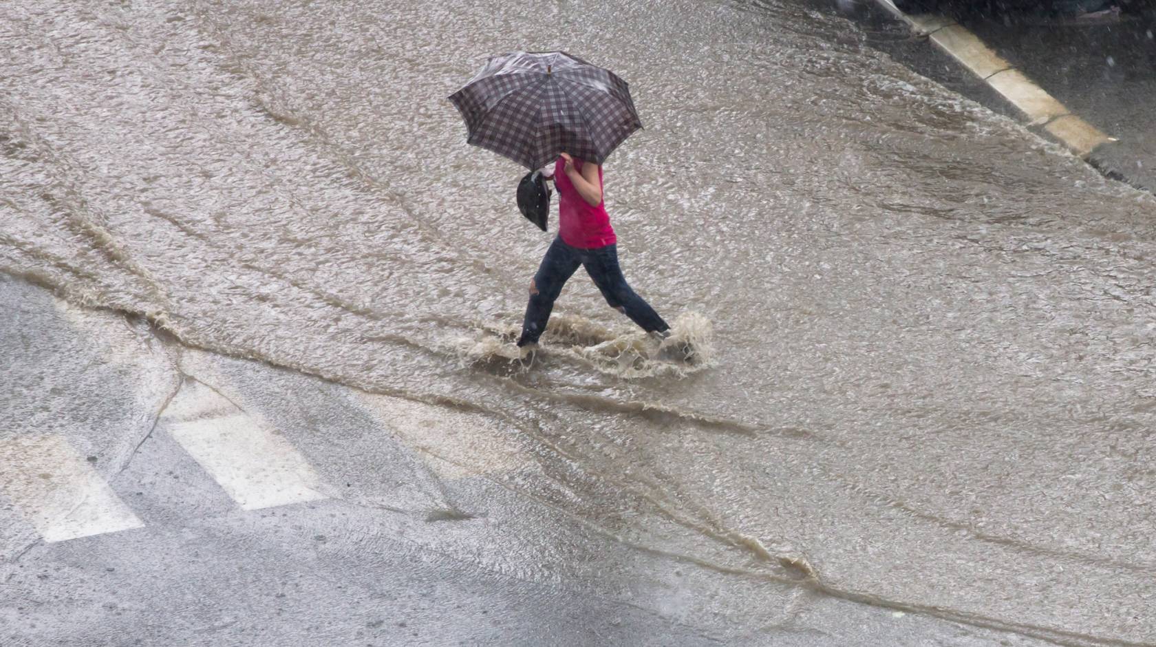 Woman walking through a flooded road with an umbrella
