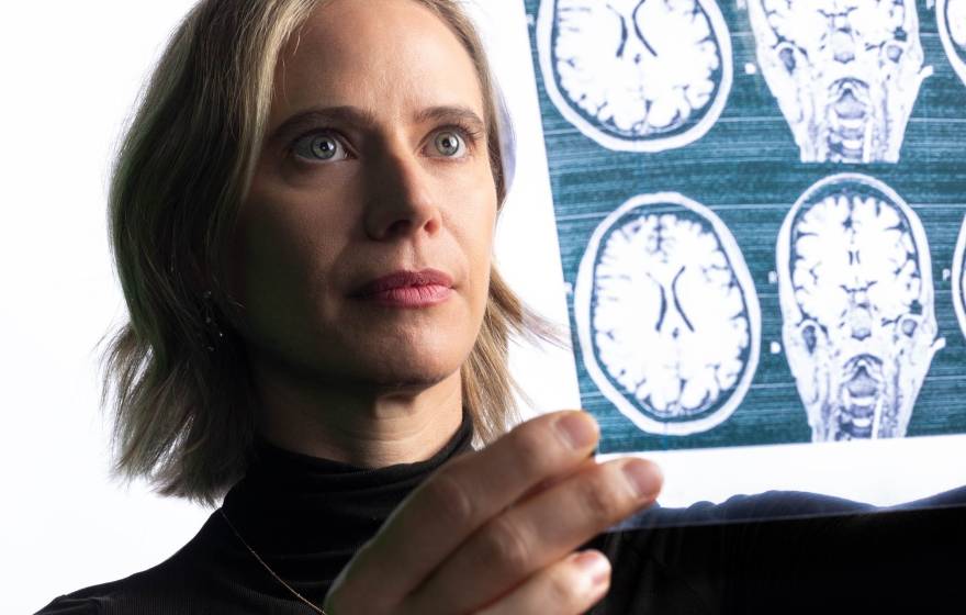 A woman holds a sheet of negatives showing scans of brains up to the light