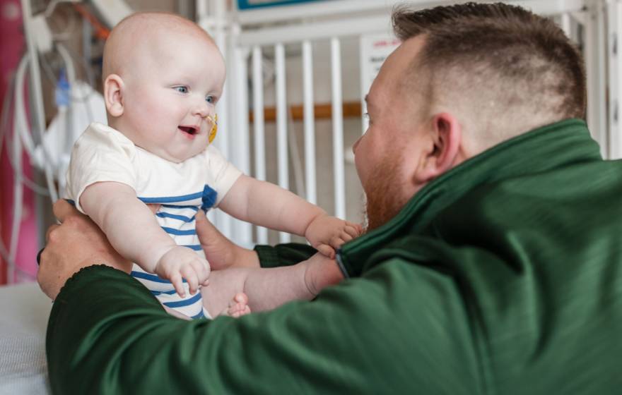 New CRISPR therapy A man in a green jacket looks at a baby in front of him, both looking excitedly at each other