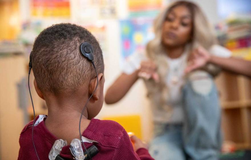 A boy wearing a black headset looks at his mom