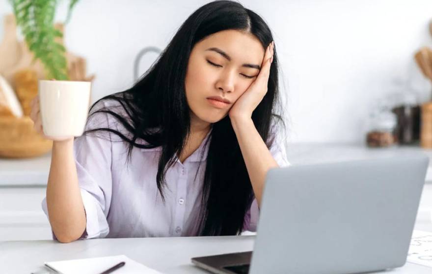 A young woman asleep in front of a laptop