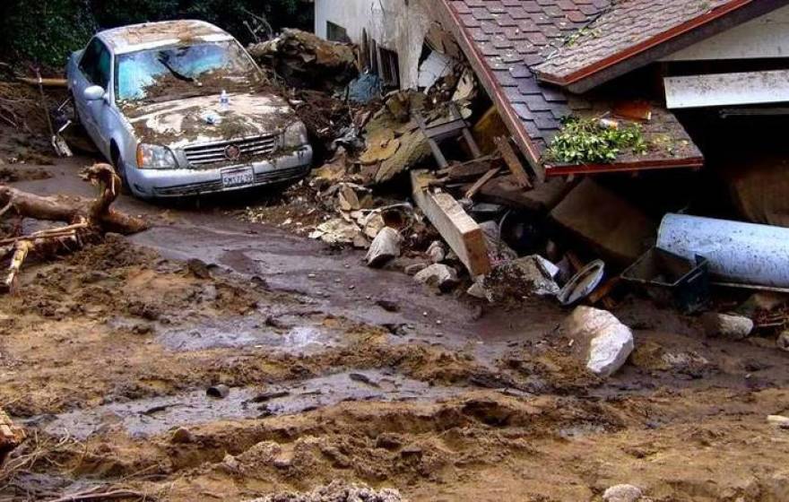 A car covered with mud and a house collapsed from a mudslide