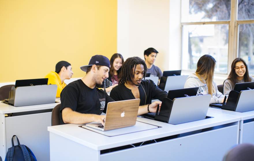 Diverse students looking at computers together in a classroom