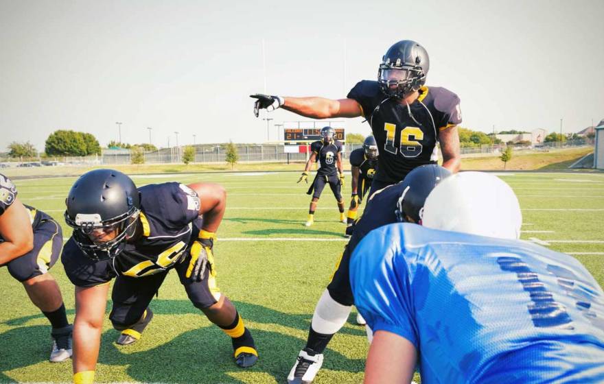 A quarterback points over an offensive line during a football game