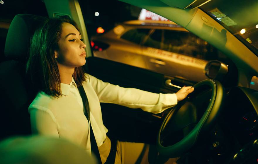 A person is leaning back and closing their eyes while driving a car.