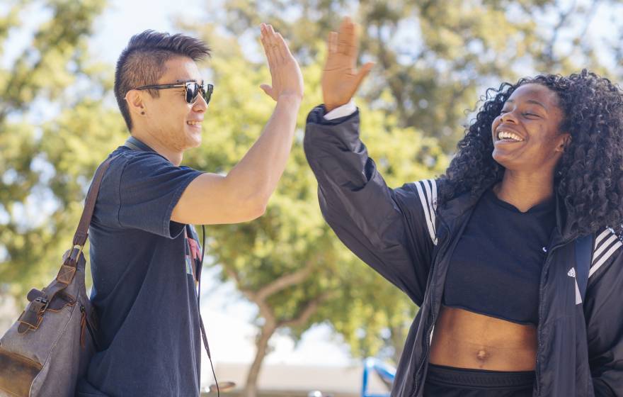 Two UC Davis students, a young Asian man and young Black woman, give each other a high five