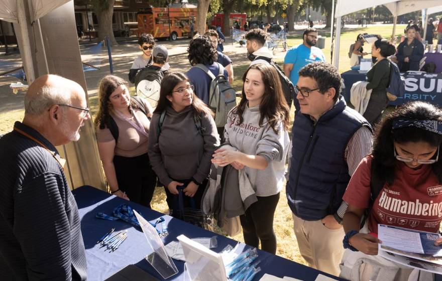 A number of undergraduates at a table outdoors during an event on campus