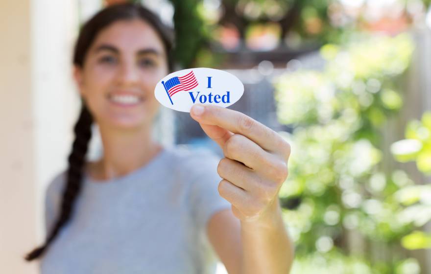 Young woman holding up an I Voted sticker