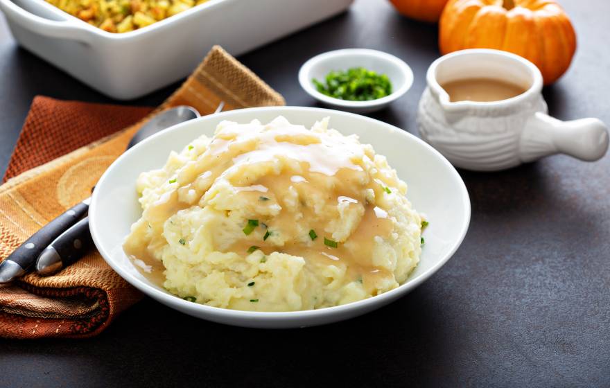 mashed potatoes, gravy and other Thanksgiving dishes on a table