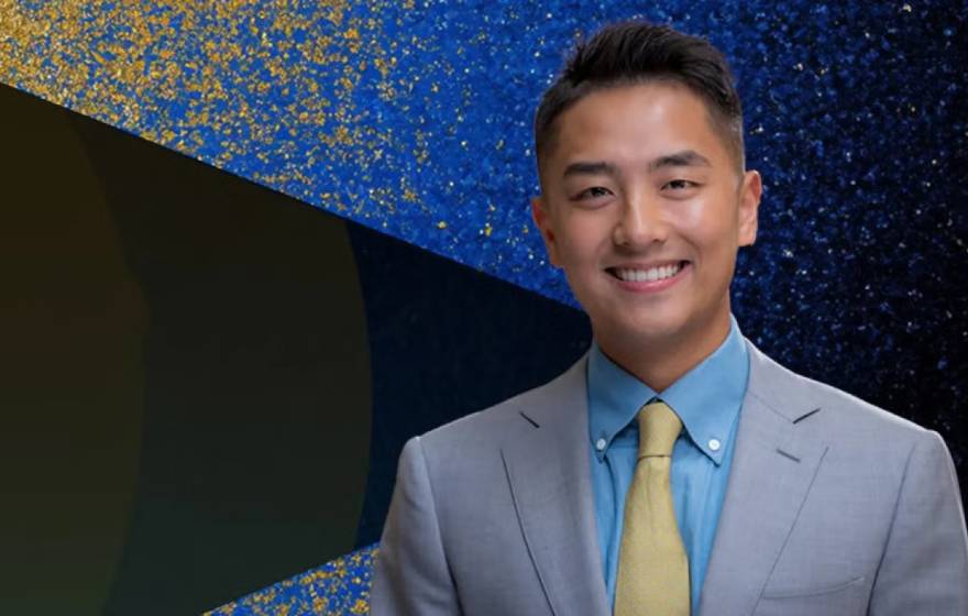Ike Zhan Young man in a suit smiling with John Wooden Leadership Fellows text on the left