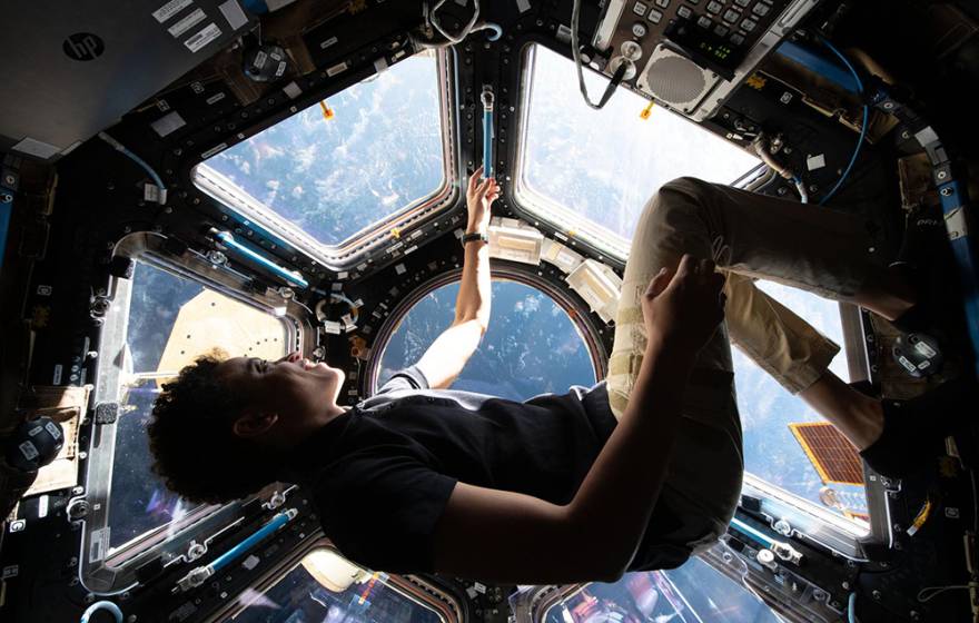 Jessica Watkins floats in the cupola of the International Space Station wearing a blue shirt and khakis