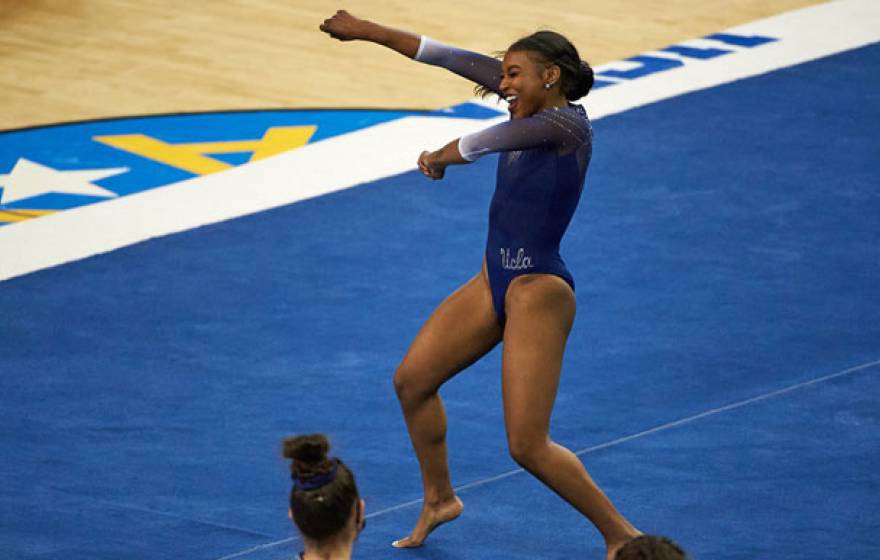 Nia Dennis smiling and pumping her fist while on the gymnastics floor