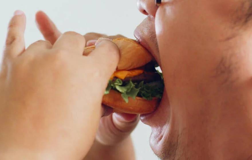 View of a man's mouth eating a burger dramatically