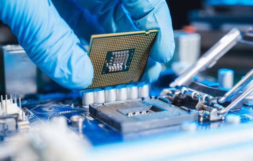 Close-up of a blue-gloved hand constructing a microchip