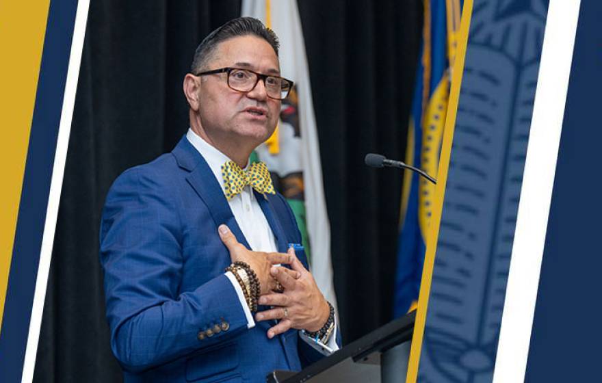Juan Sánchez Muñoz in a blue suit speaks at a podium, holding both hands to his chest