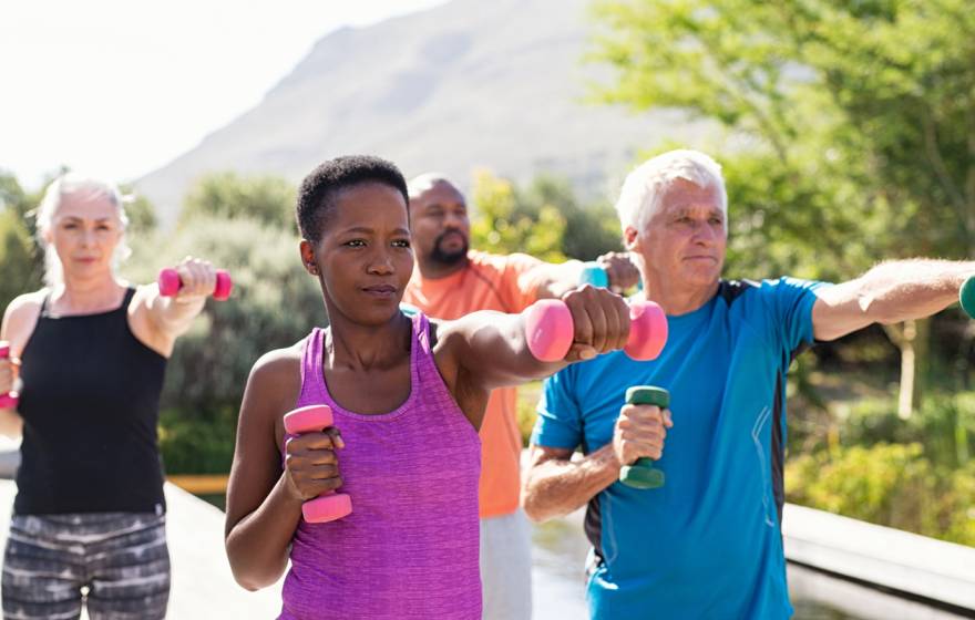 Older adults working out together with weights outdoors