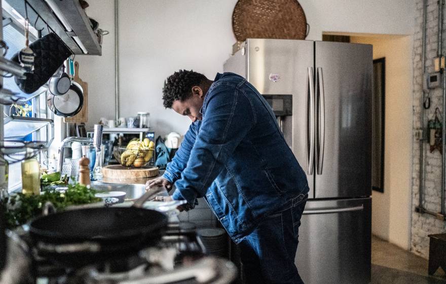 Man leans against counter in a kitchen, looking overwhelmed