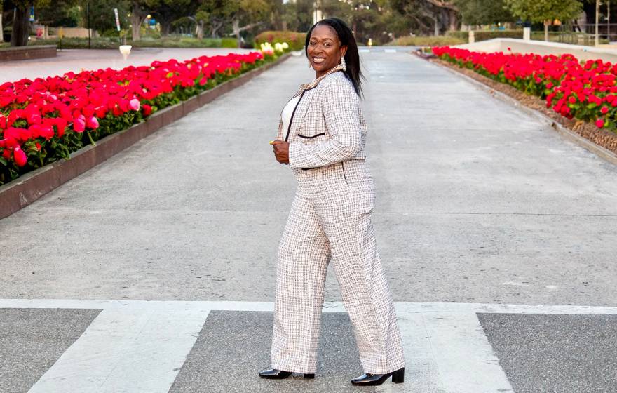 Sonya Brooks walks in a crosswalk across a street lined with red tulips