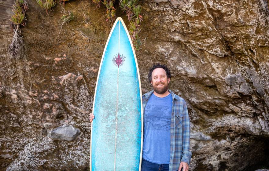 David Schulkin stands with his surfboard