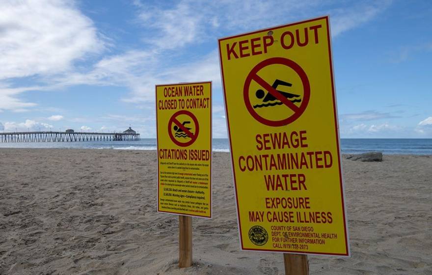 Closed beach An empty beach with a pier in the background on a nice day bears signs that say Keep Out Sewage Contaminated Water and Ocean Water Closed to Contact Citations Issued