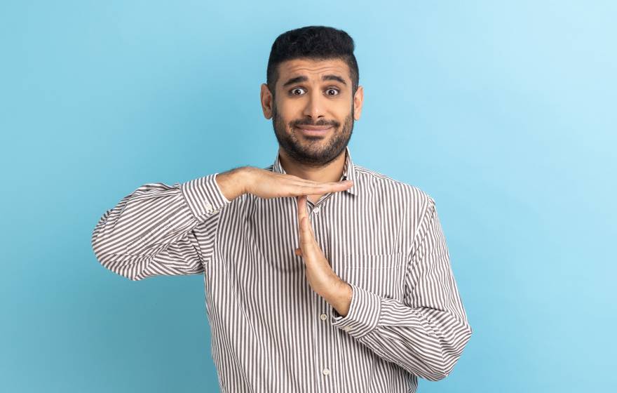 A bearded South Asian man making the timeout gesture