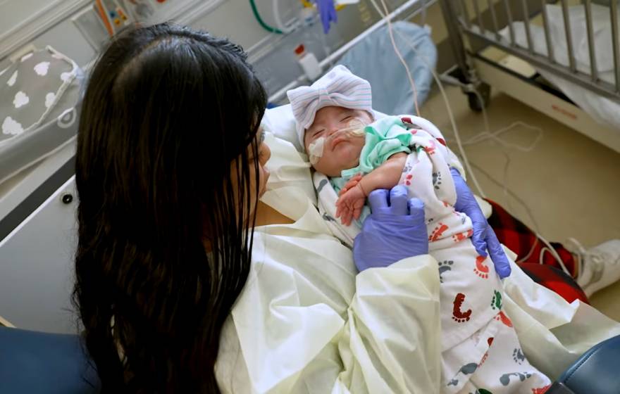 UC Davis Health saves baby A young woman holds a young baby in her lap at a hospital
