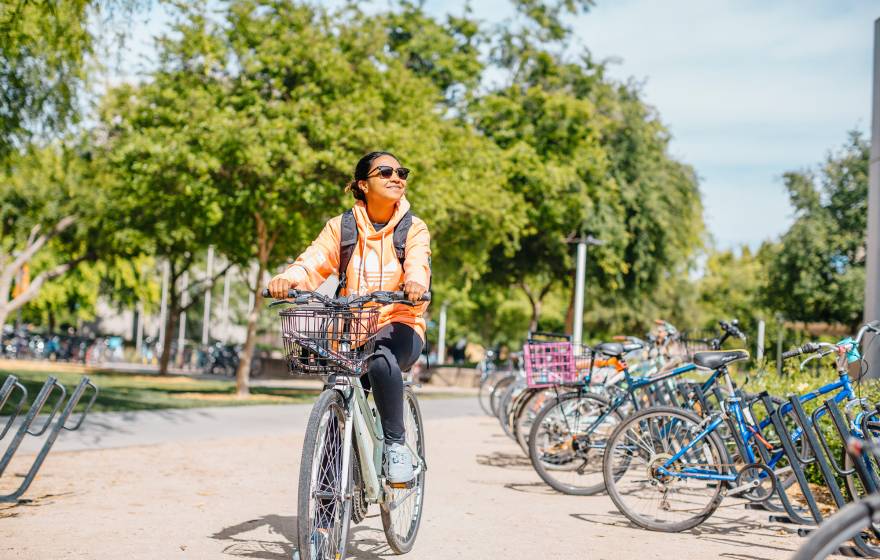 A student smiling in sunglasses riding a bike