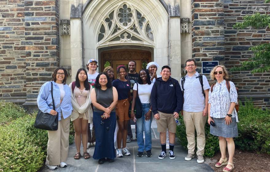 A group of people outside an old stone building with an arched entryway