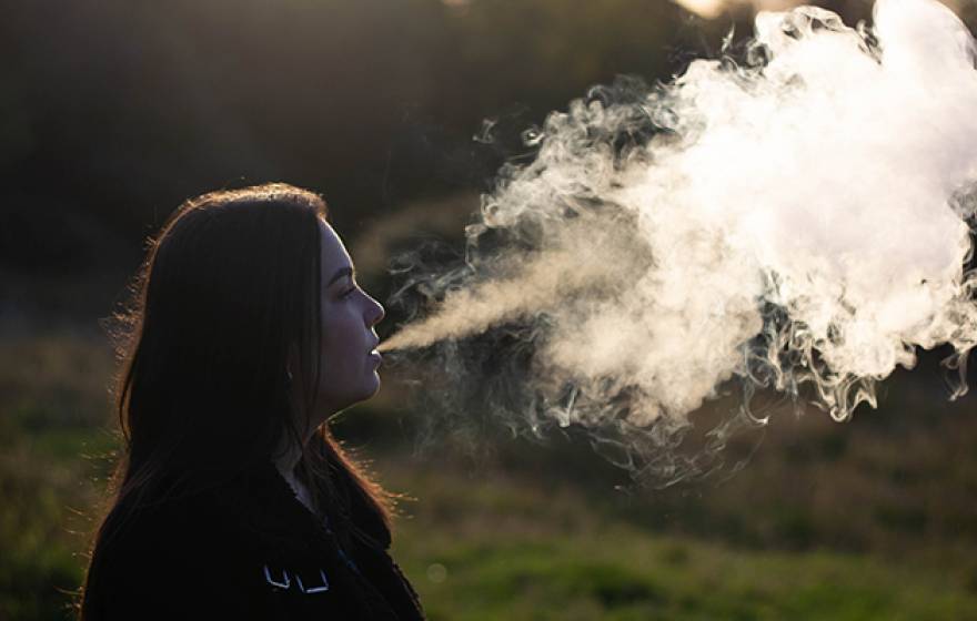 Young woman vaping big cloud of smoke