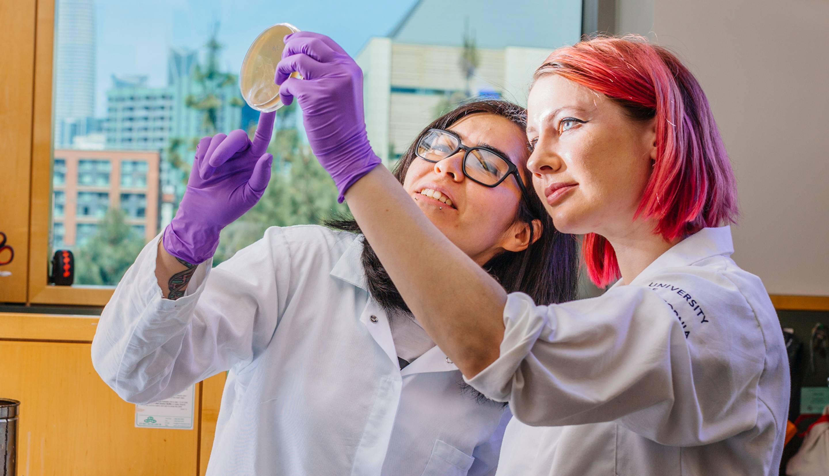 Two female UCSF students looking at a petri dish in the lab