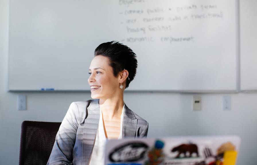 Woman at laptop smiles looking out window