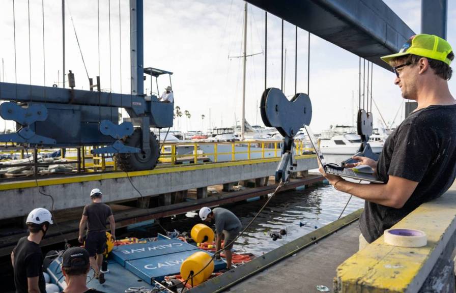 A man watches a construction team work on CalWave on a dock