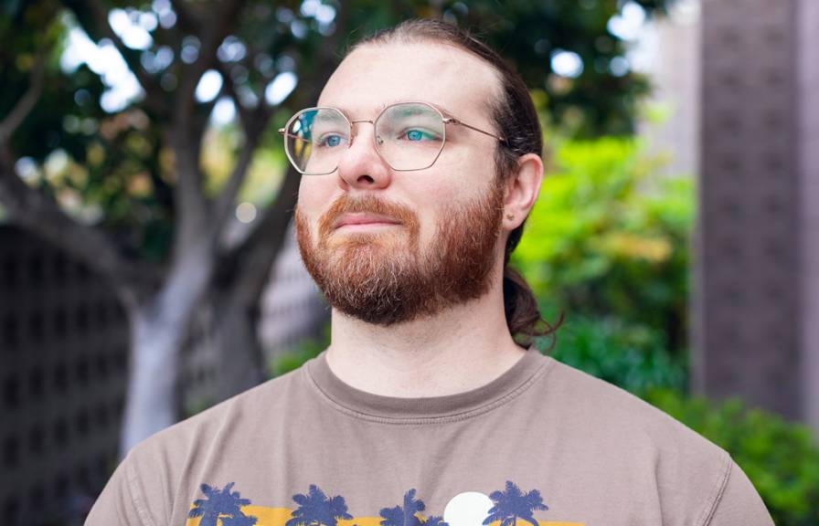 Portrait of a man with glasses, a beard and a pony tail looking off into the distance