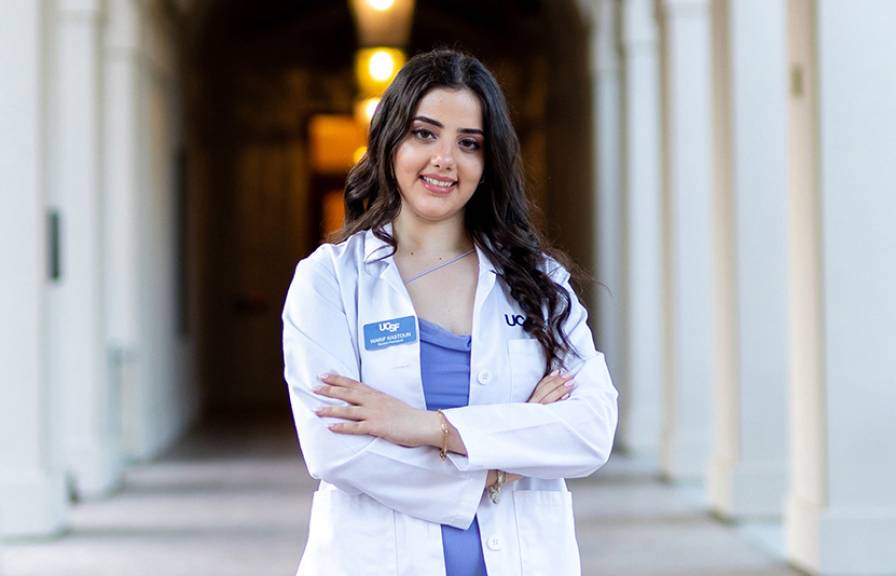 A smiling woman wearing a white doctor's coat