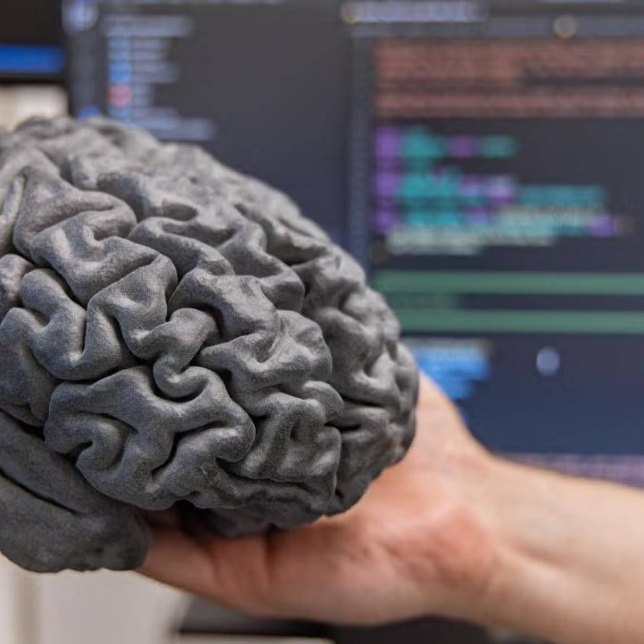 Brain-computer breakthrough A hand holds a gray model of a human brain