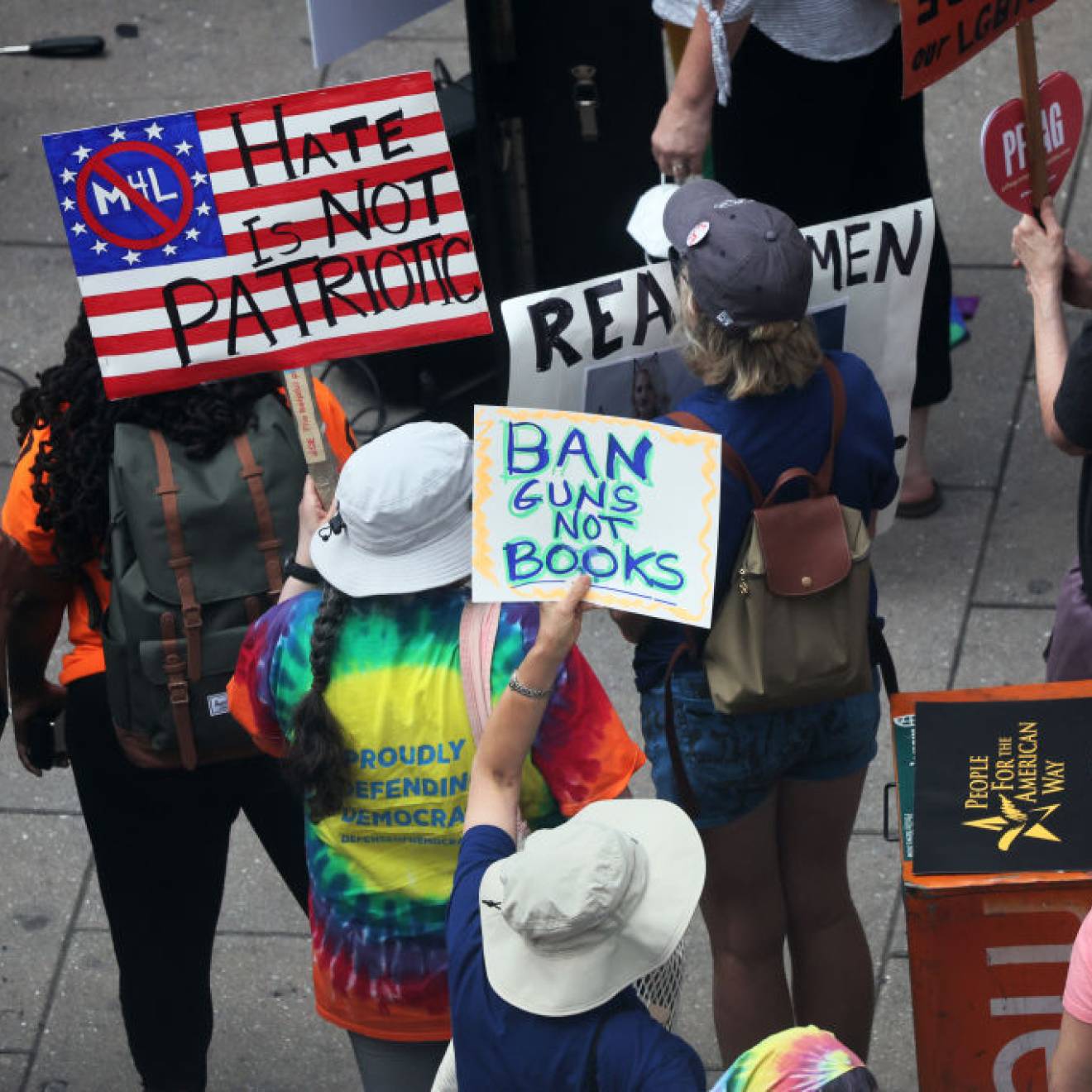 People at a protest holding signs, one reading "Ban guns not books"