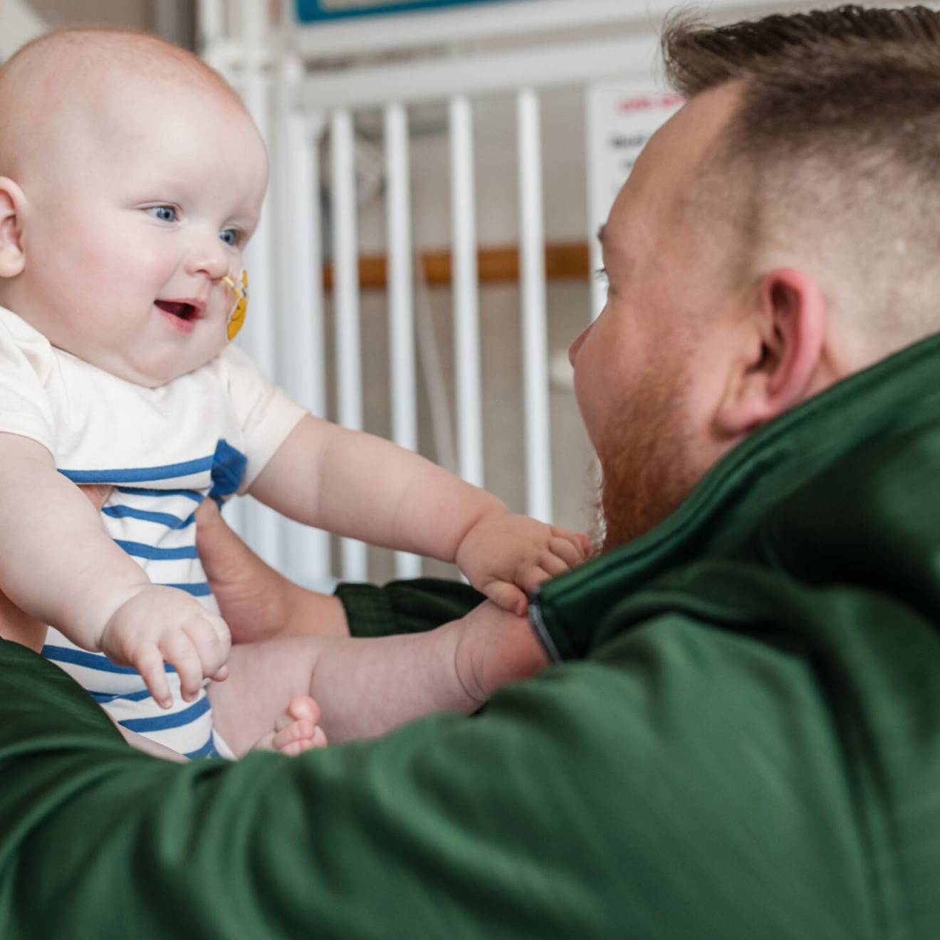 New CRISPR therapy A man in a green jacket looks at a baby in front of him, both looking excitedly at each other