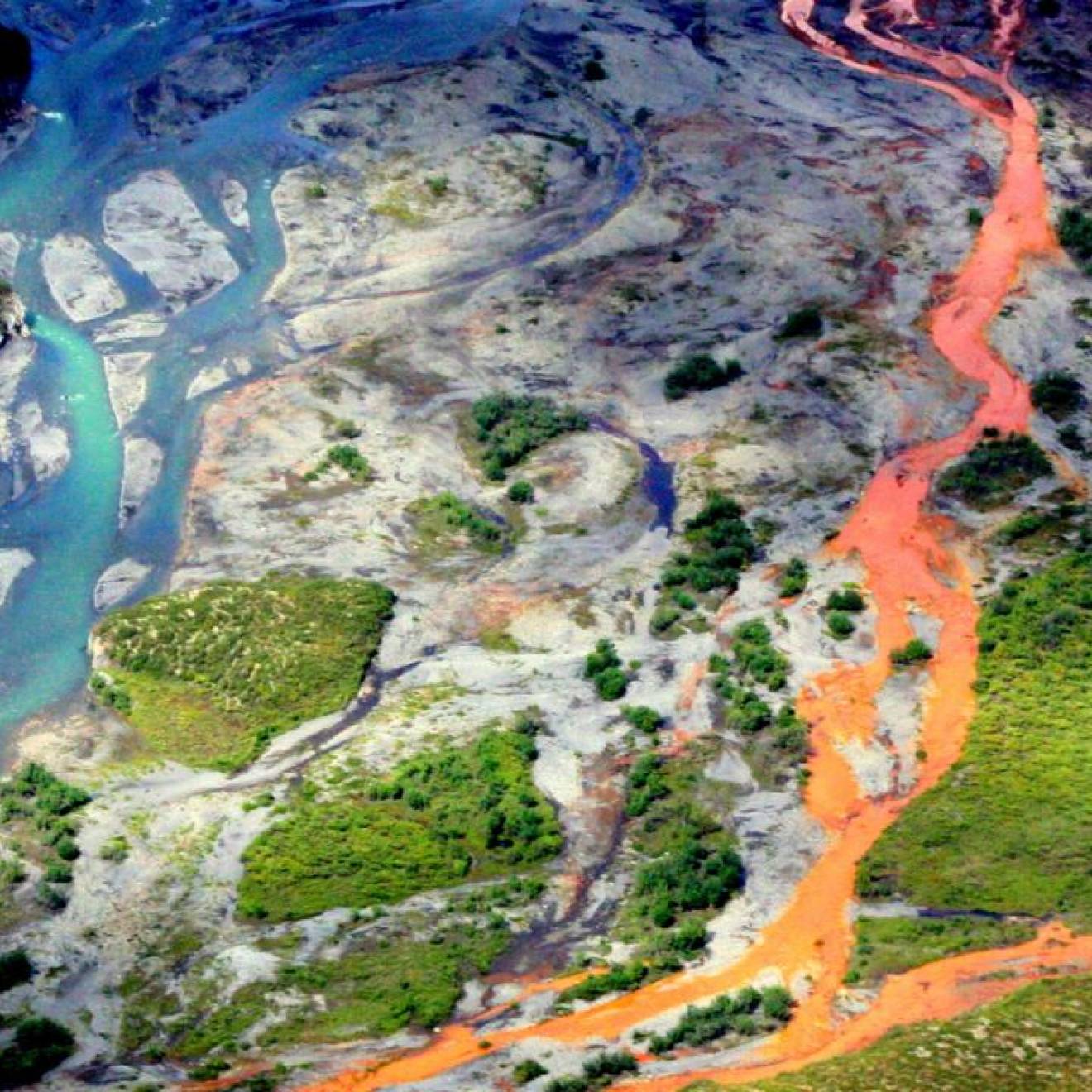 Aerial view of a braided river flowing through a tundra. The channels on the right side of the image are bright orange.