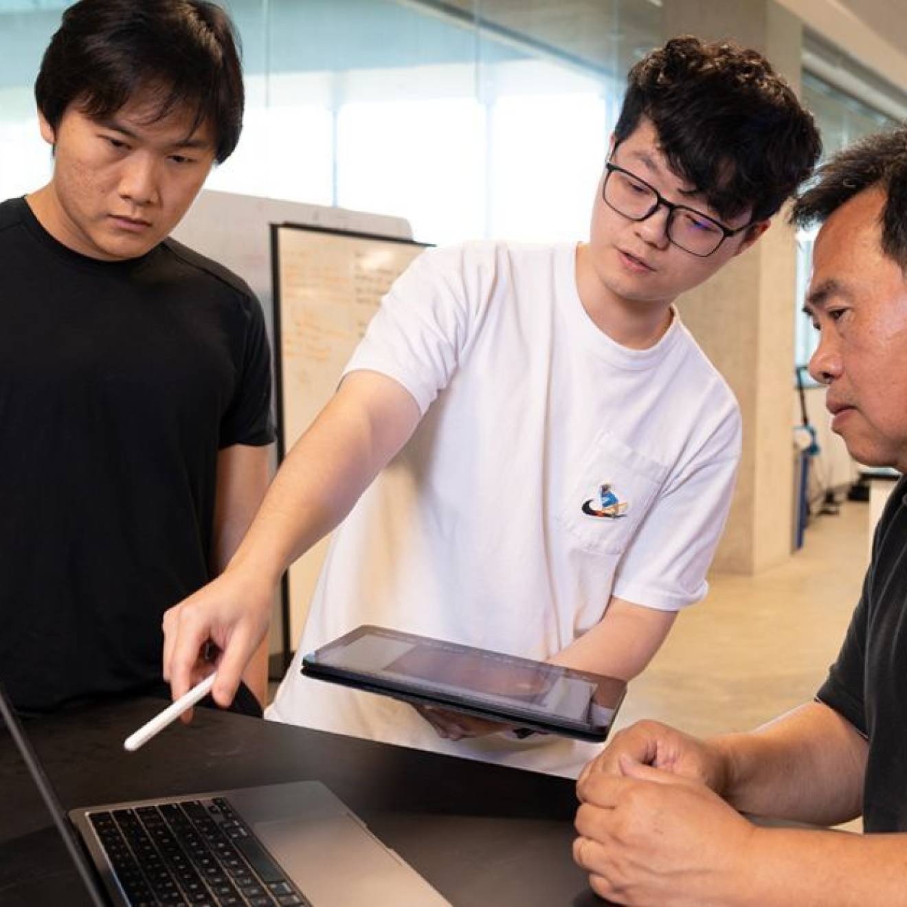 Two students and a professor look at a computer