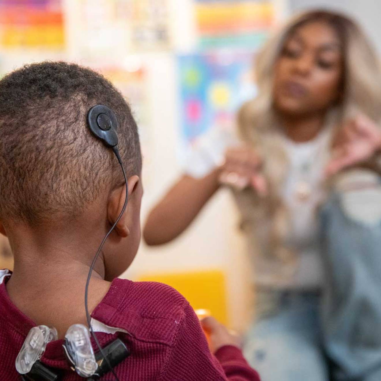 A boy wearing a black headset looks at his mom